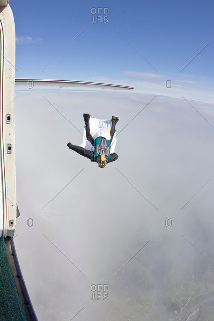 Mid adult man flying above clouds in wingsuit