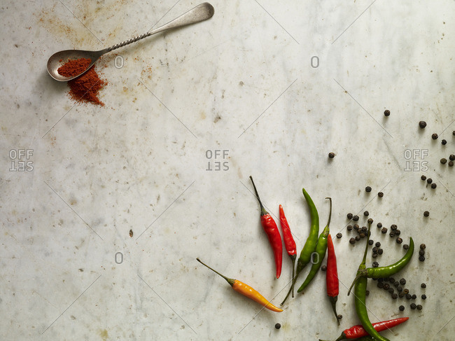 Peppers, peppercorns and crushed red pepper on a marble surface
