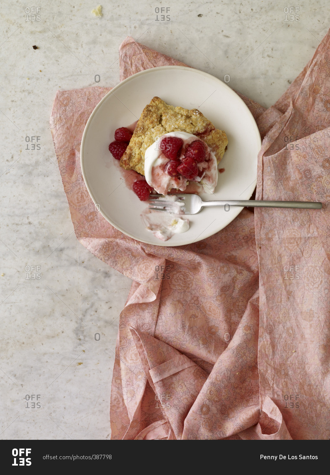 Strawberry shortcake on a plate with a fork and a pink floral cloth