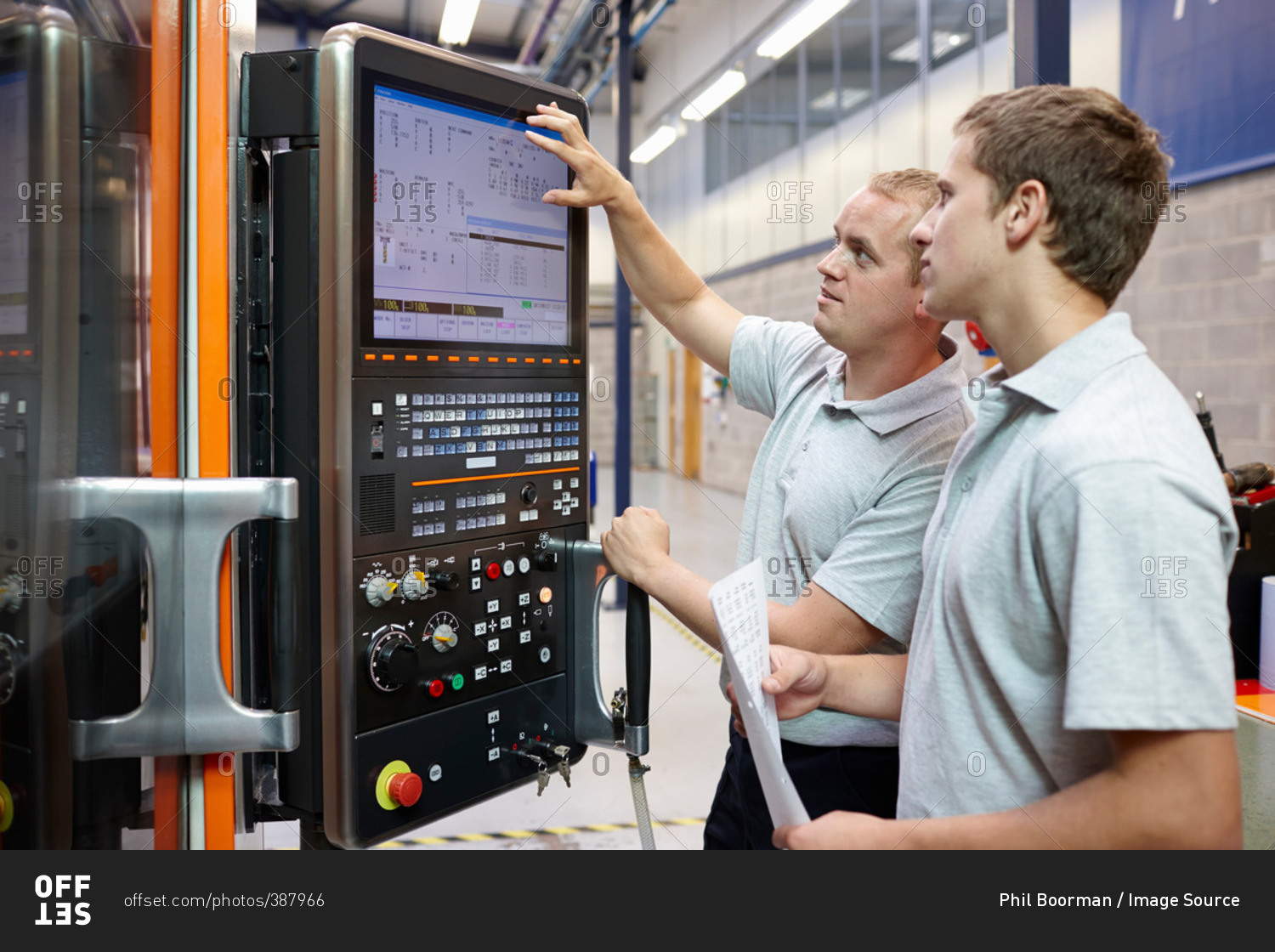 Workers looking at computer monitor in engineering factory