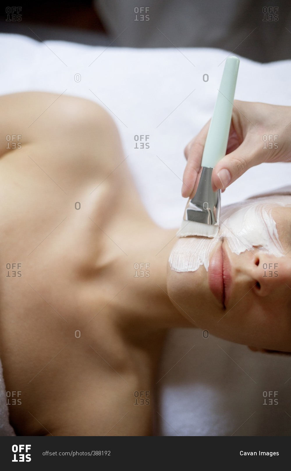 Overhead view of cream being applied on woman's face in spa