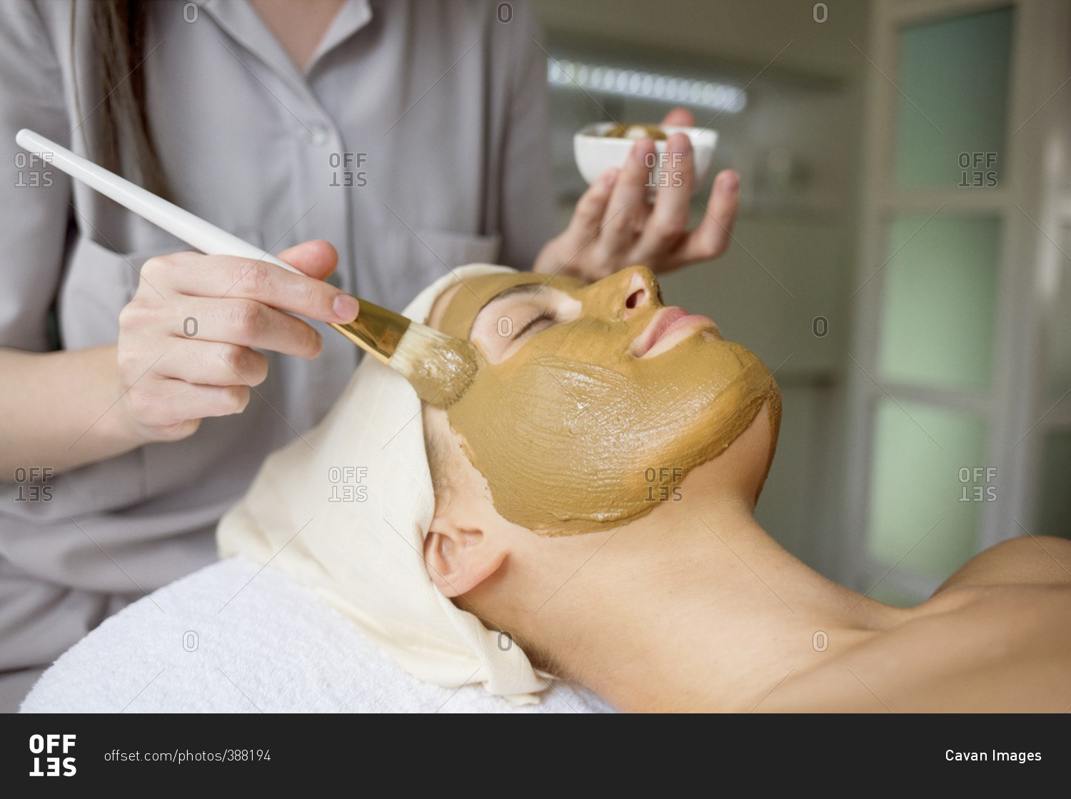 Female therapist applying facial mask on woman's face in spa