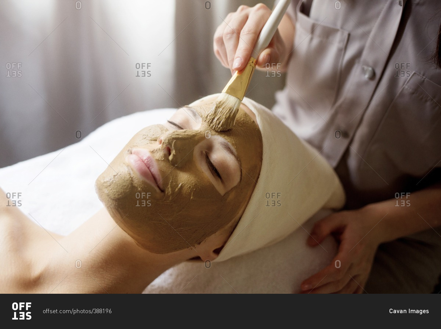 Therapist applying facial mask on woman's face in spa