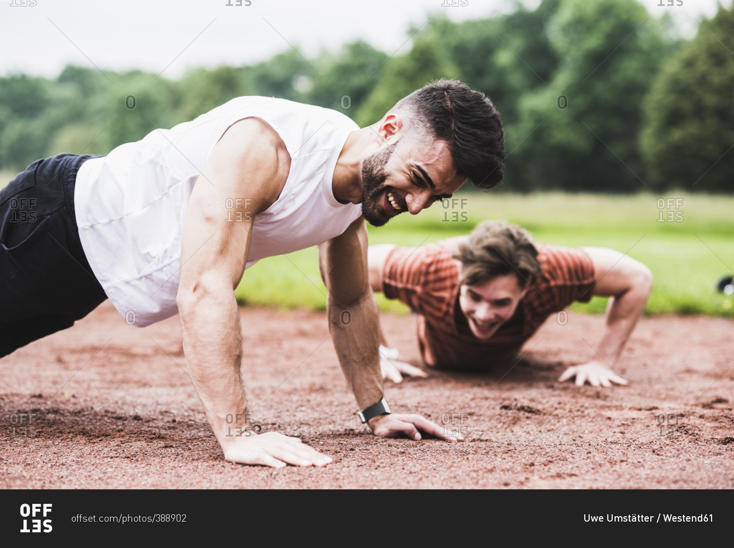Two athletes doing pushups on sports field