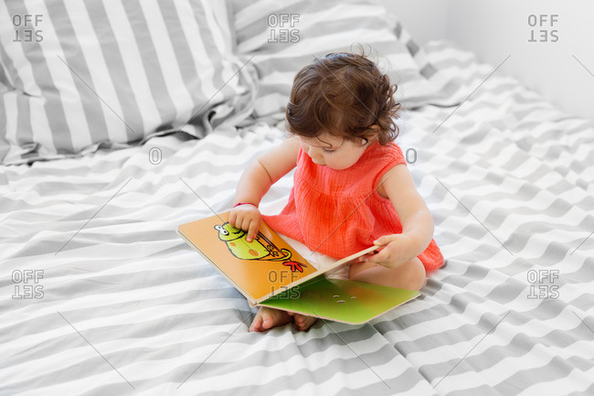 Toddler girl pointing at an illustration in a board book