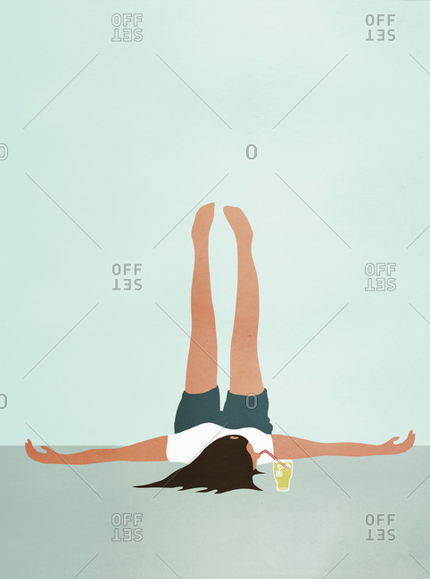 Woman lying on floor with feet up while drinking cold drink