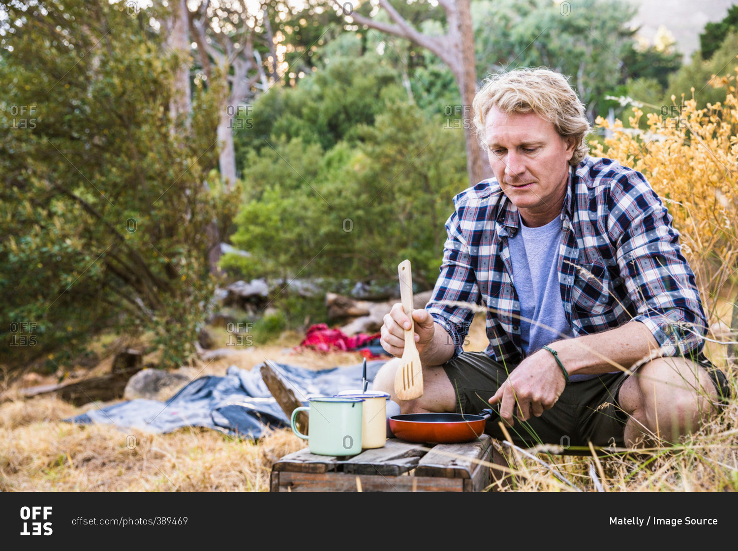 Mature man frying breakfast on camping stove in forest