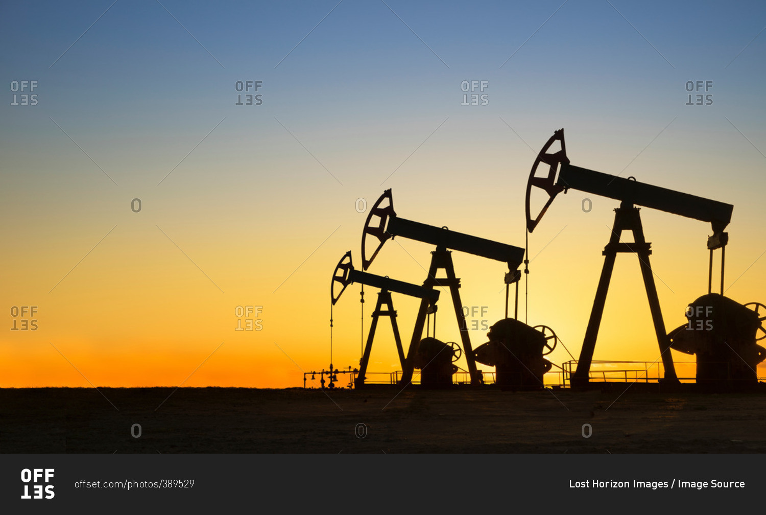 Silhouette of oil wells in desert at sunset