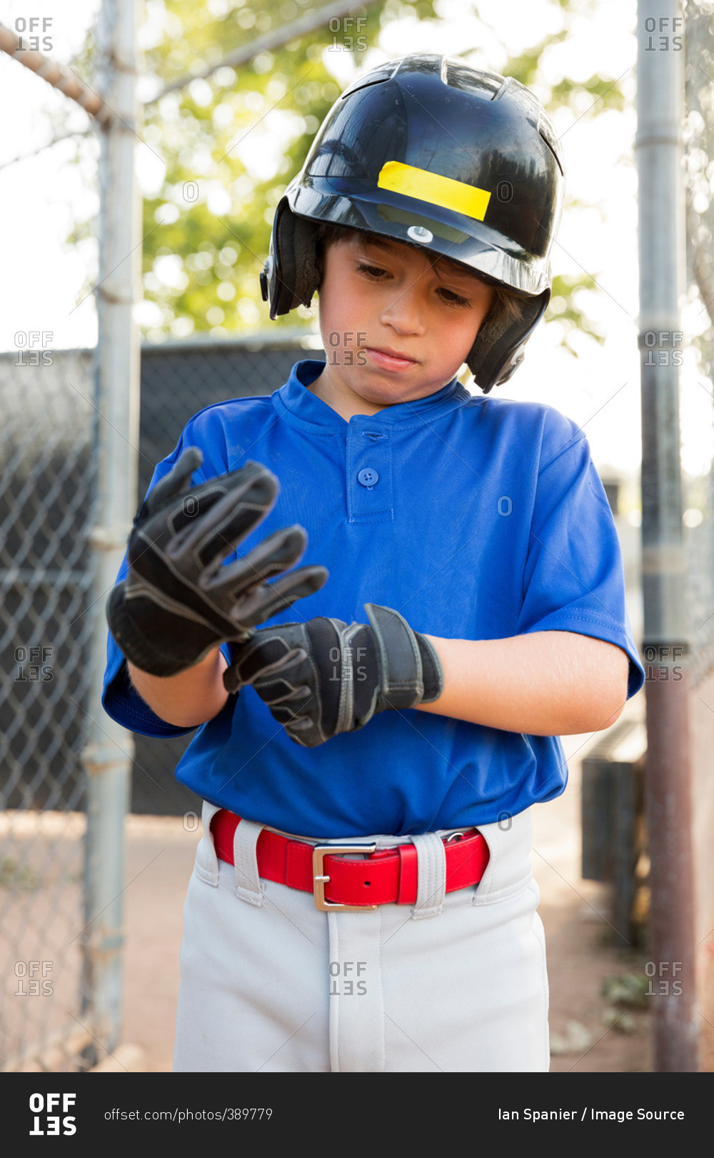 Boy putting on baseball gloves at baseball field