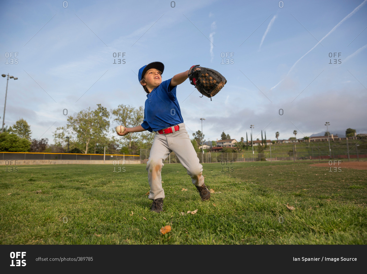 Boy throwing ball at practice on baseball field stock photo OFFSET