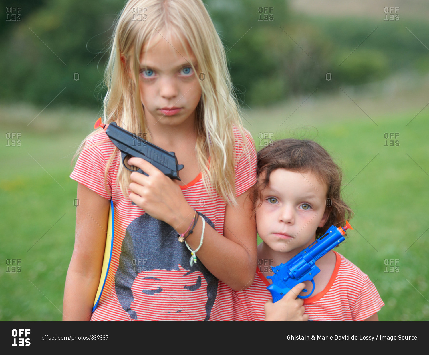 Portrait of two young sisters, holding toy guns
