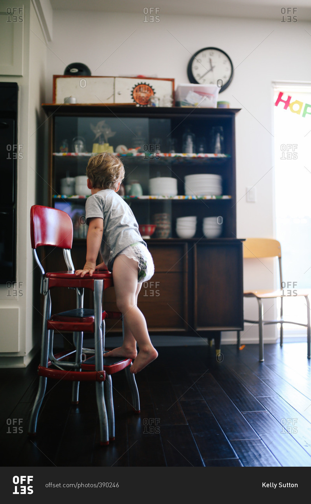 Boy standing on  foot rest of chair