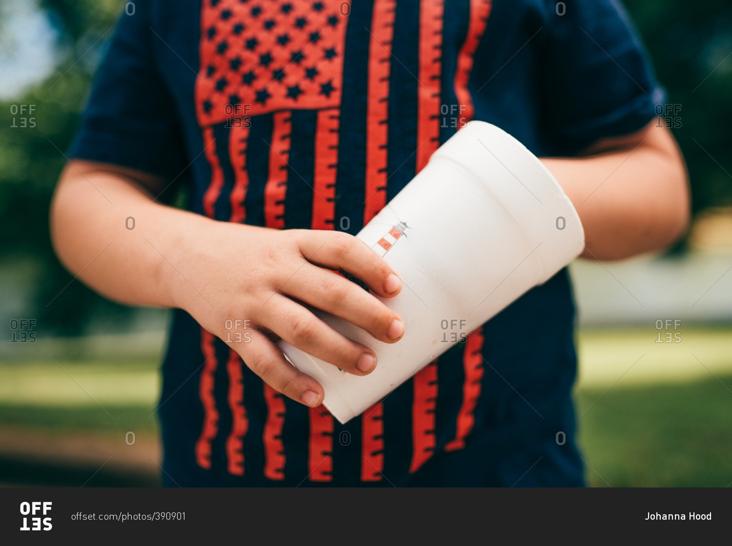 Close up of child wearing American flag shirt while holding a cup