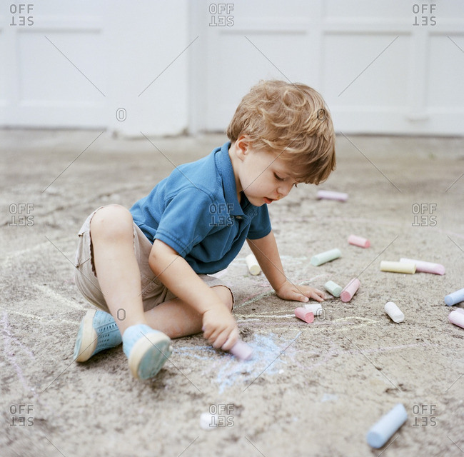 Toddler boy drawing on driveway with chalk
