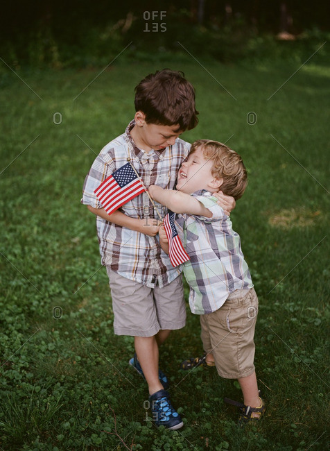 Two young brothers with American flags hug each other