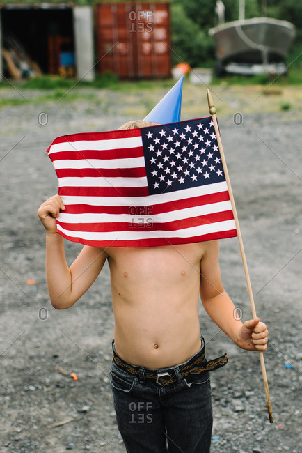 Boy wearing a birthday hat holding the American flag