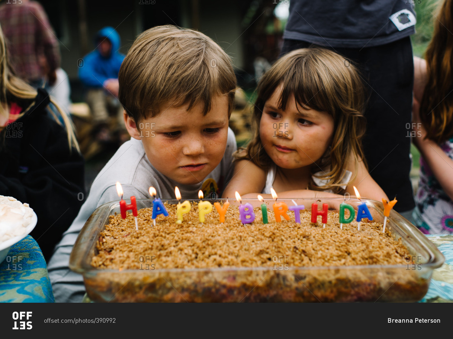 Children at a party looking at a cake that has happy birthday spelled out in candles
