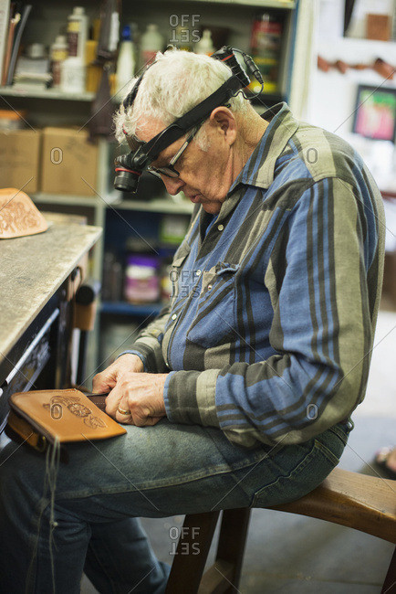 A mature man working on a leather piece