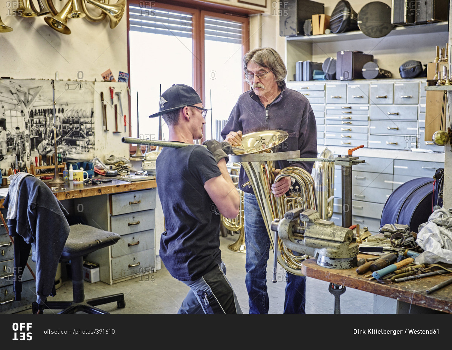 Two instrument makers repairing brass instrument in workshop