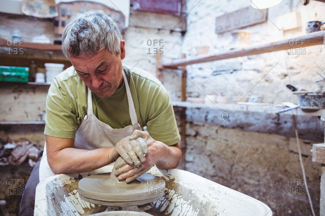 Craftsman making container while sitting in potter workshop