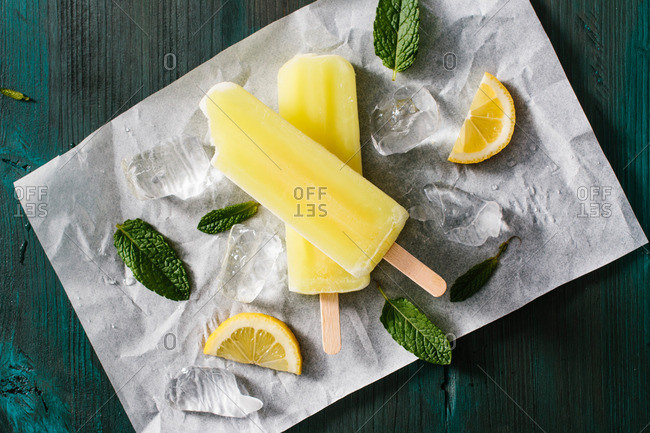 Lemon popsicles with mint and ice chunks on paper
