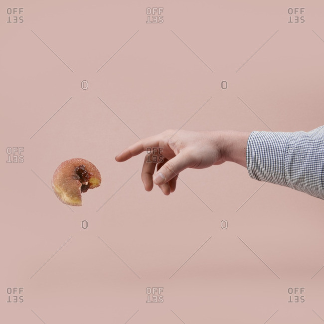 Hand reaching to touch a jelly donut
