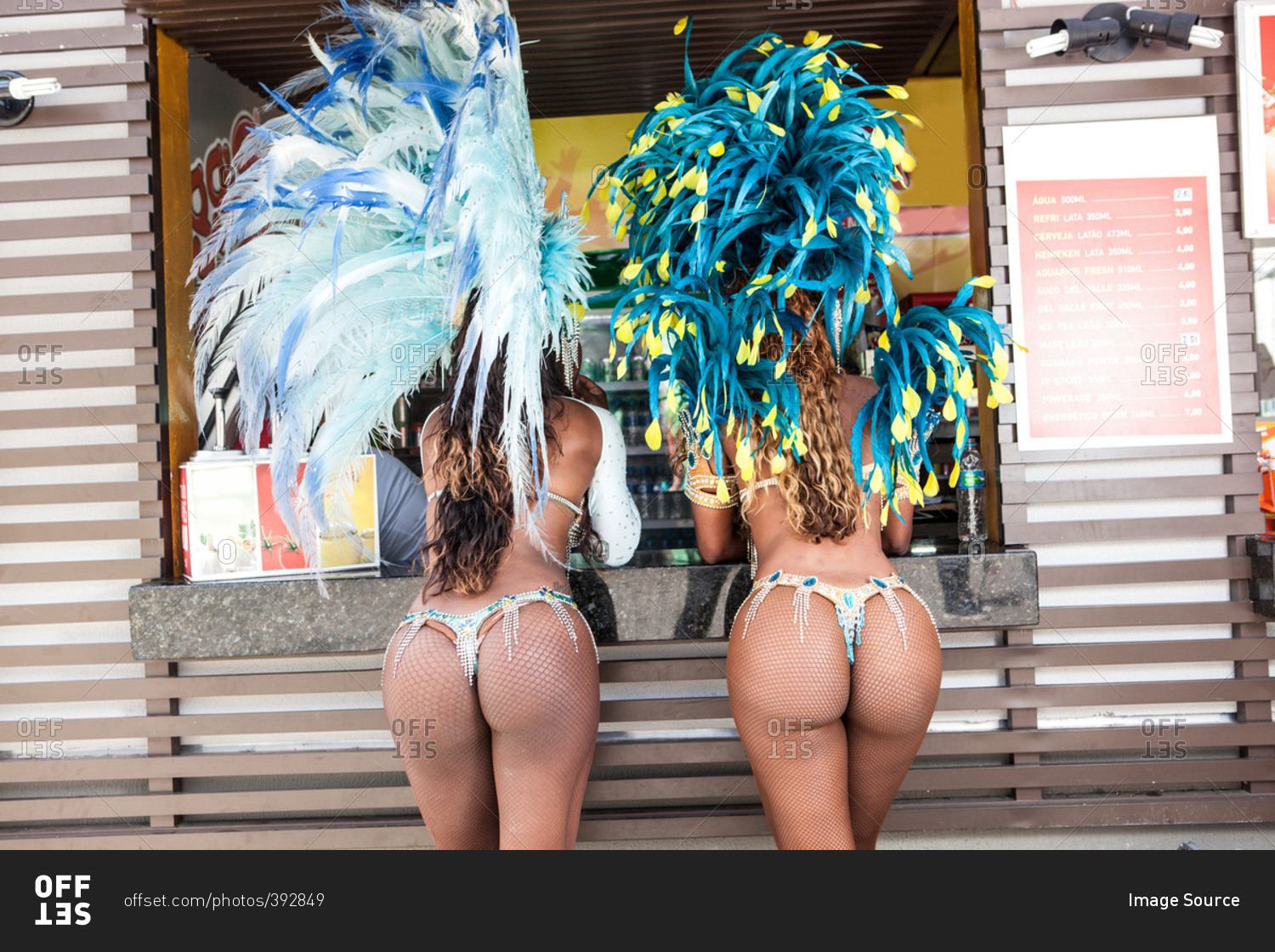 Rear view of samba dancers in costume by food stall, Rio De Janeiro, Brazil