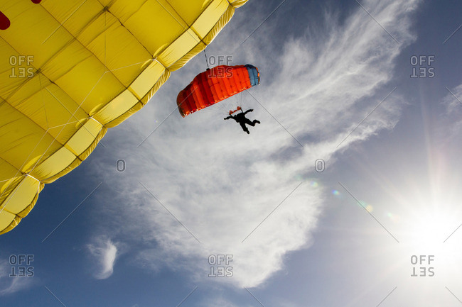 Female skydiver steering yellow parachute