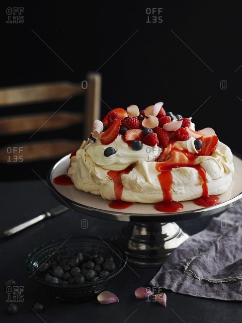 Pavlova with strawberries, blueberries and rose petals