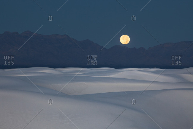 Full moon setting at dawn over San Andres Mountains near White Sands National Monument