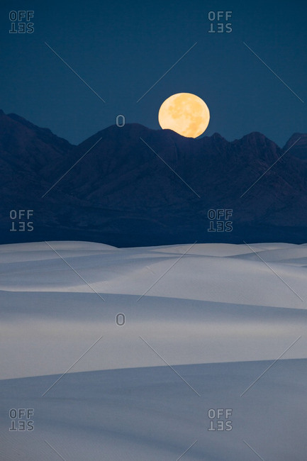 Full moon setting at dawn behind San Andres Mountains near White Sands National Monument, New Mexico