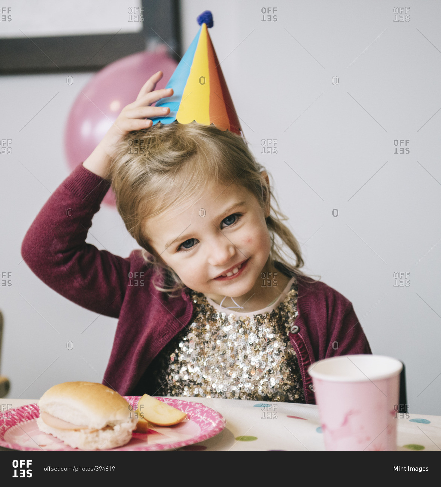 A young girl in a party hat at a birthday party
