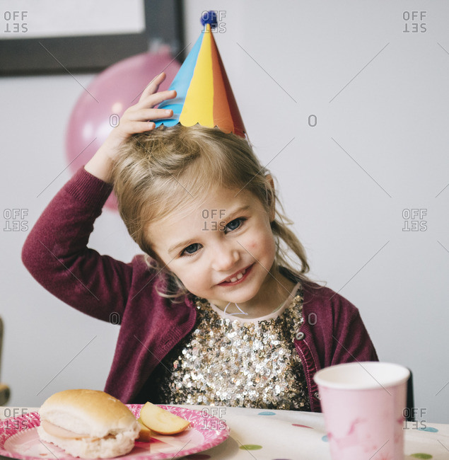A young girl in a party hat at a birthday party