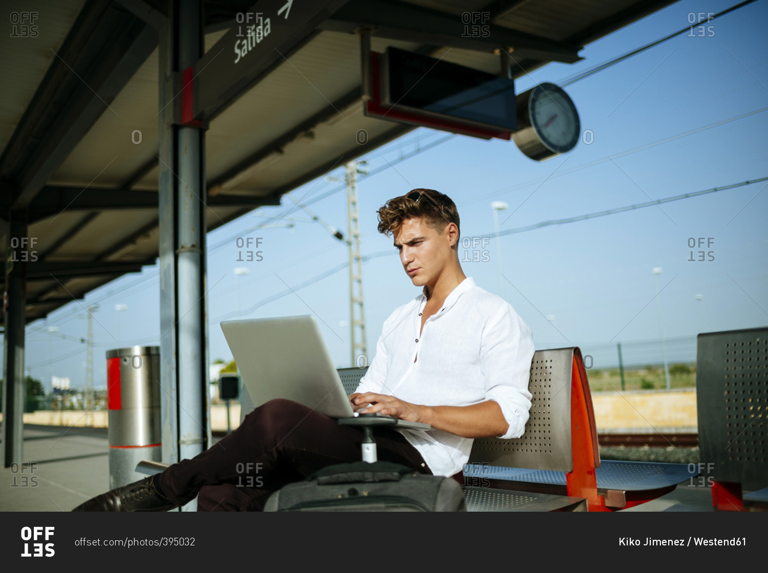 Young man using a laptop at station platform