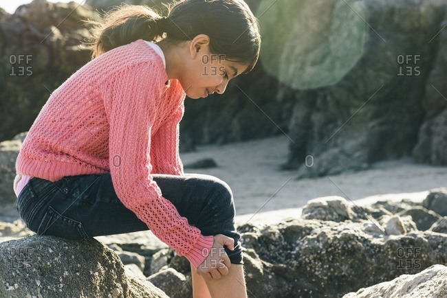 Girl pulling up jeans leg on beach