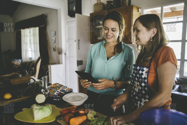 Women checking tablet while cooking