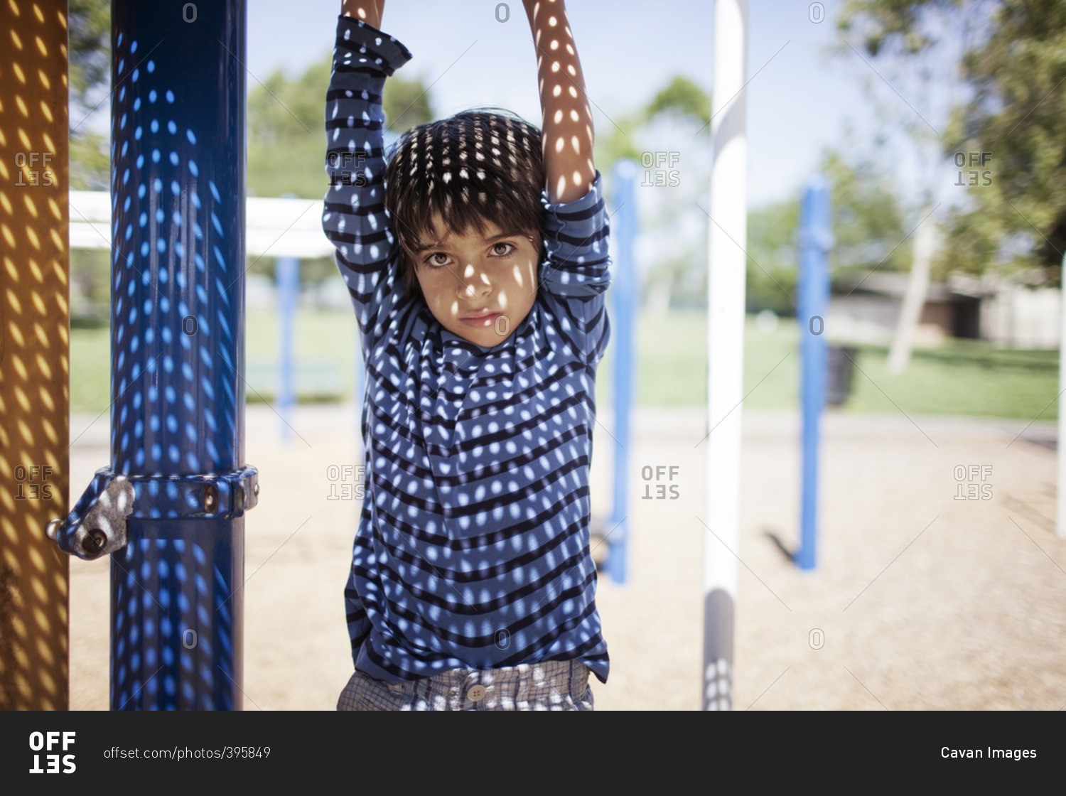 Portrait of boy hanging from outdoor play equipment at playground