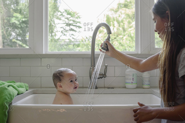 giving baby bath in kitchen sink