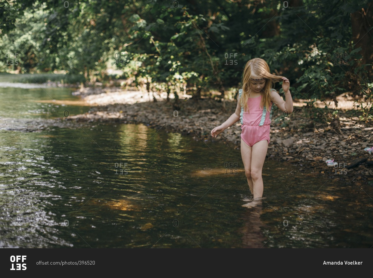 Girl getting into a river to swim stock photo OFFSET