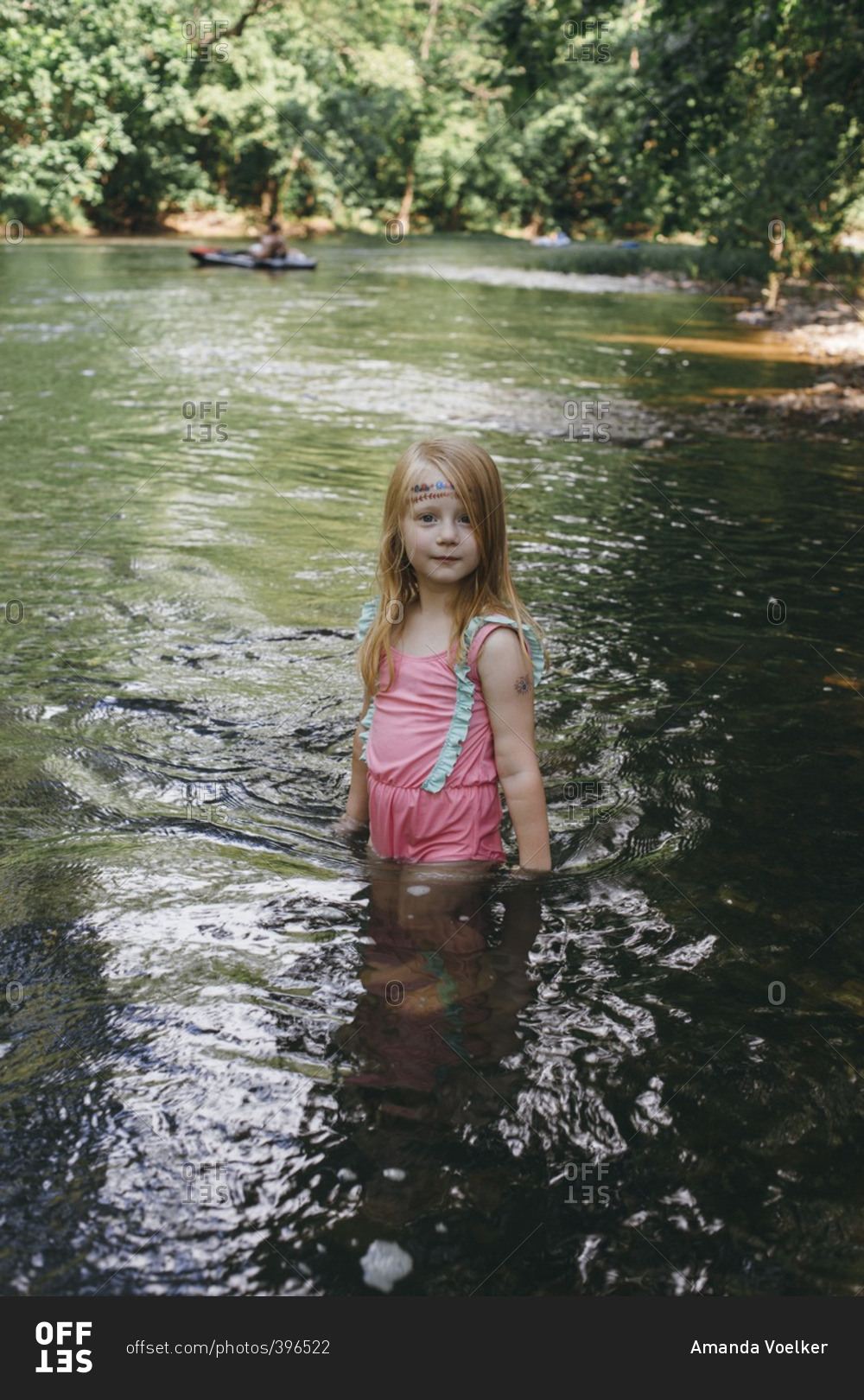 Girl standing in a river stock photo - OFFSET