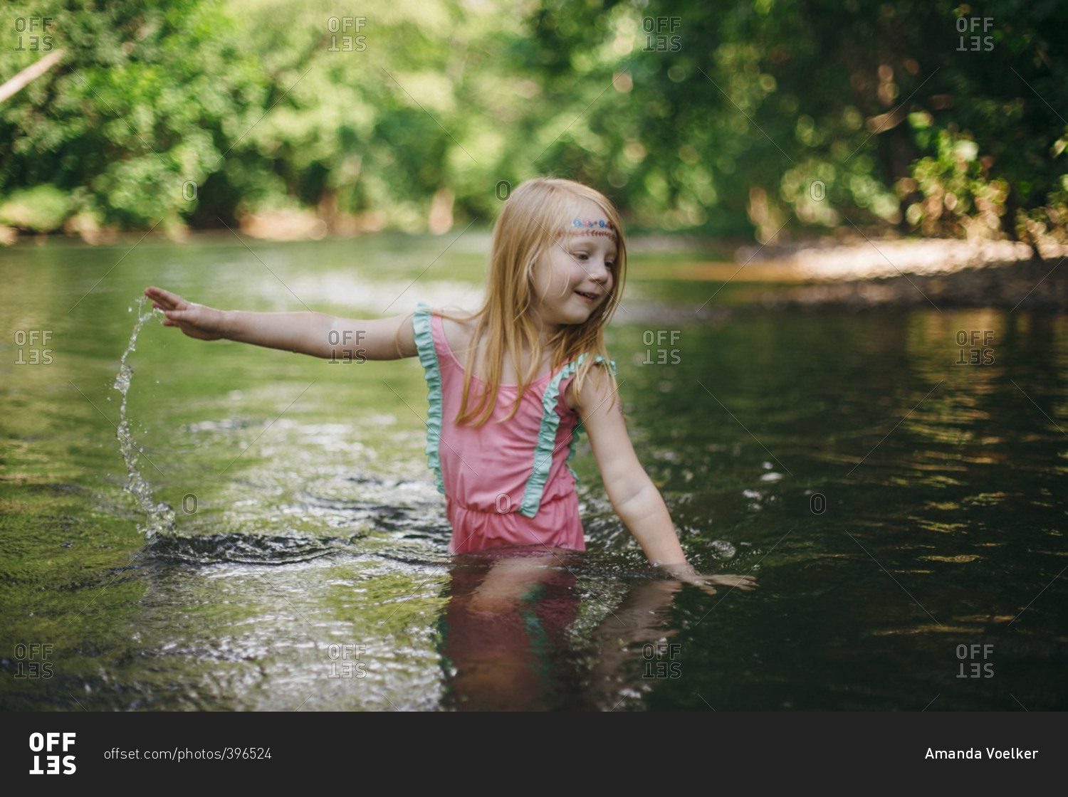 Little girl swinging arms in the river water stock photo - OFFSET