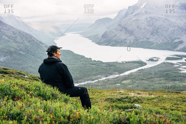 Sweden, Lapland, Kaitumjaure, Kungsleden, Male hiker sitting and looking at river in mountain valley