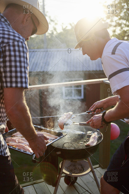 Sweden, Sodermanland, Two men grilling fish