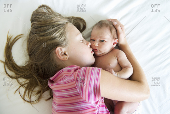 Sweden, Girl lying on bed with newborn sister (0-1 months)