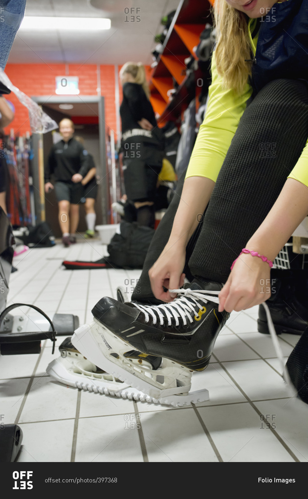 Sweden, Young woman tying shoelaces in locker room