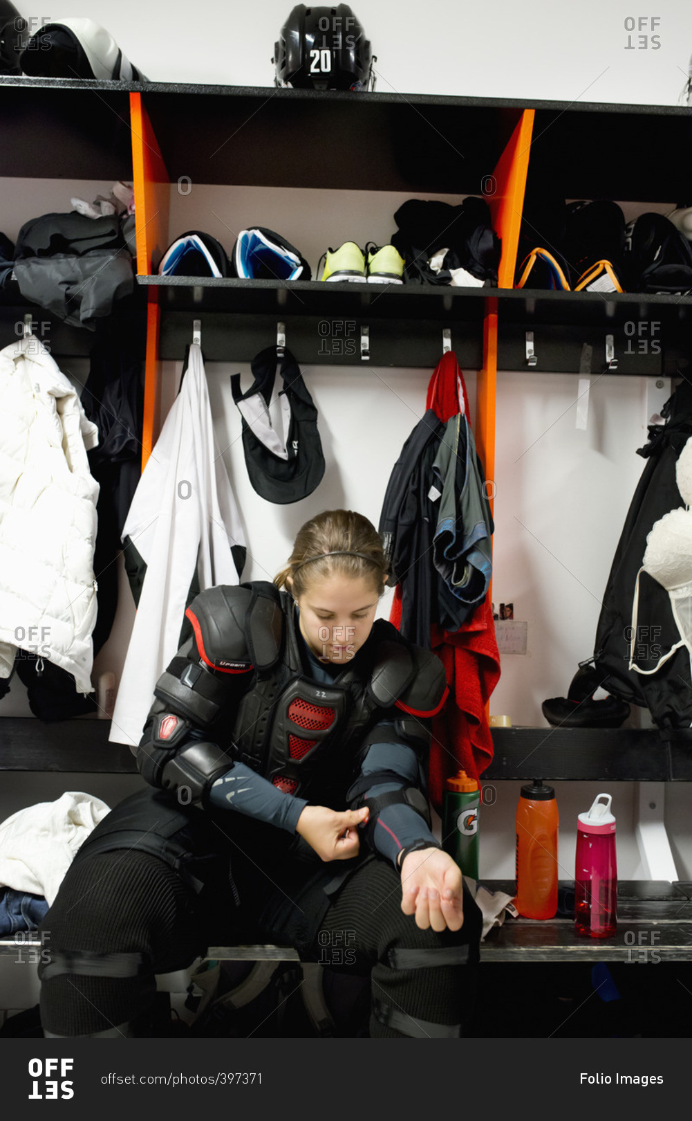 Sweden, Young ice hockey player sitting on bench and getting ready in locker room