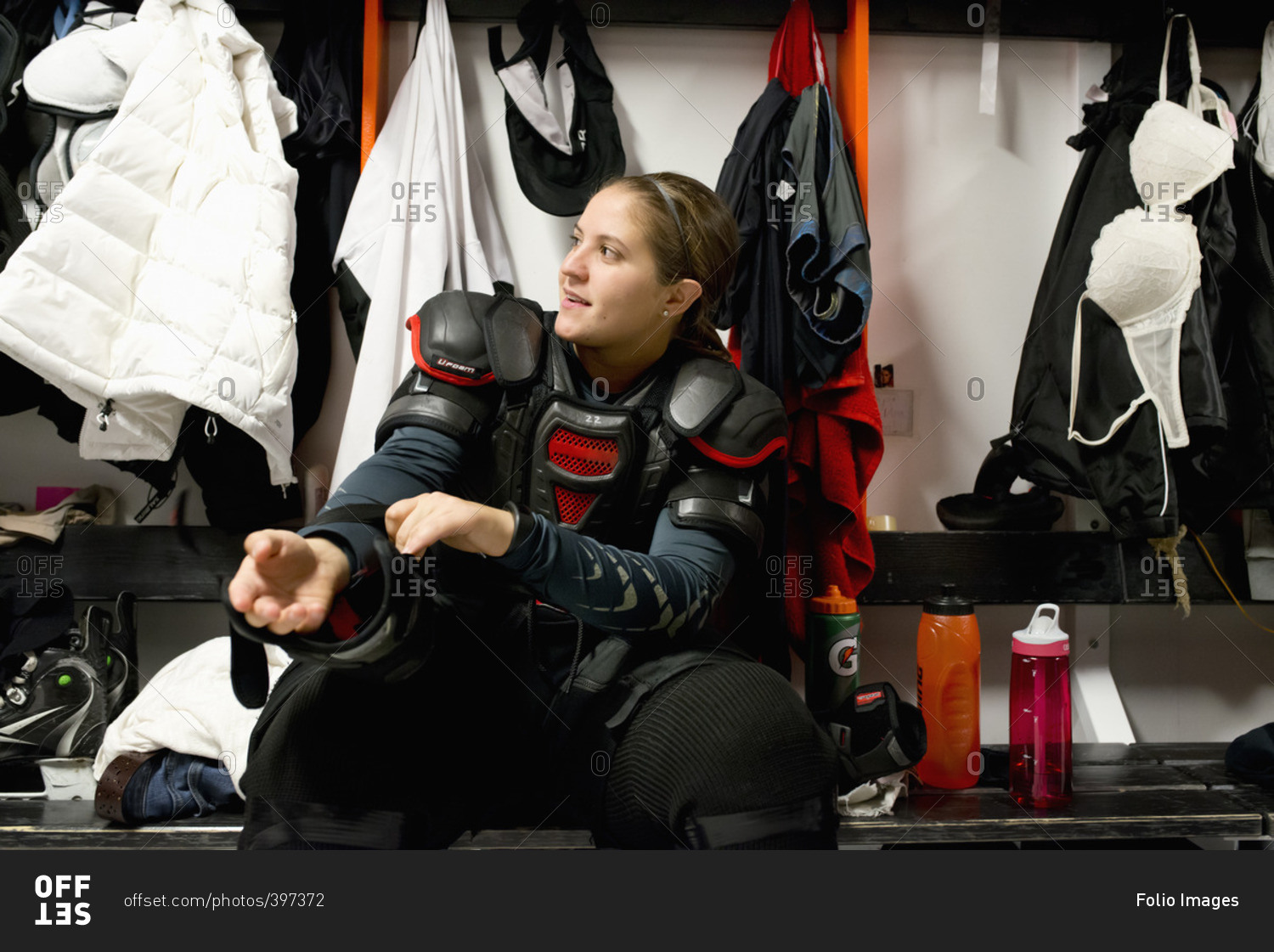 Sweden, Young ice hockey player sitting on bench and getting ready in locker room