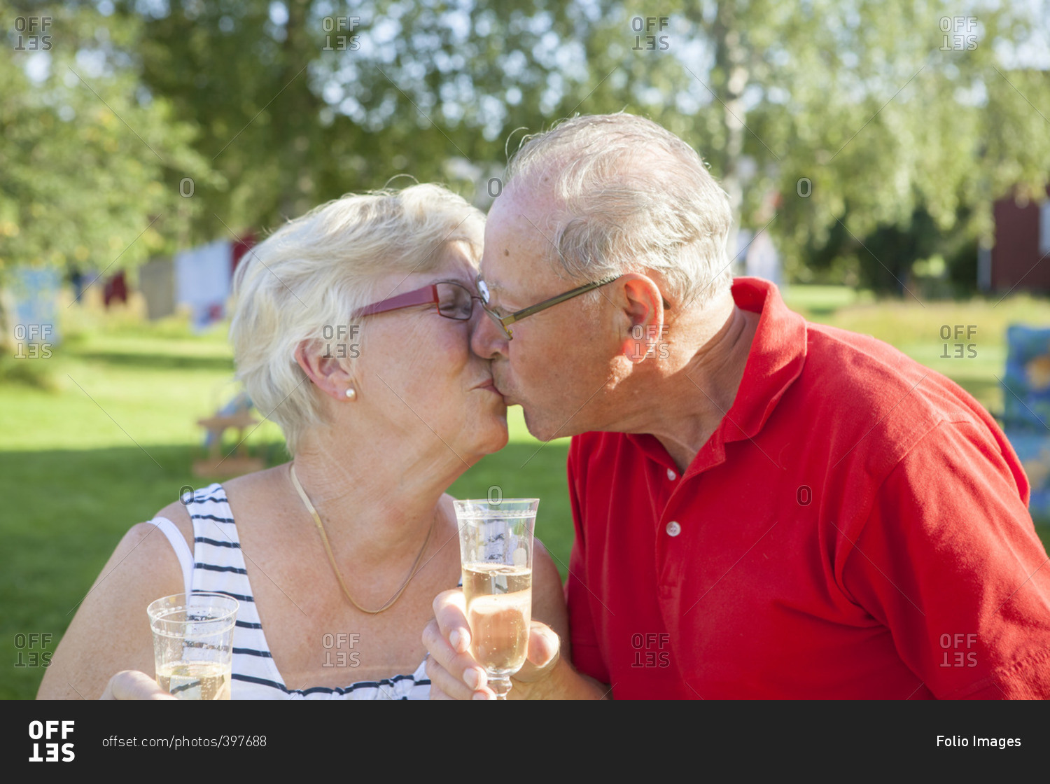Sweden, Senior couple toasting with champagne flute and kissing