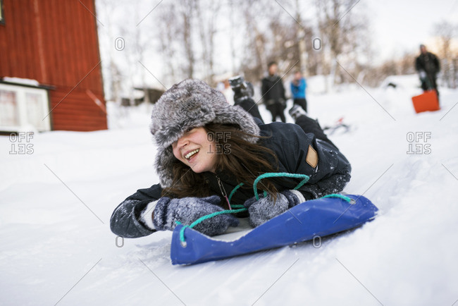 Sweden, Lapland, Hemavan, Young woman sliding on toboggan in winter
