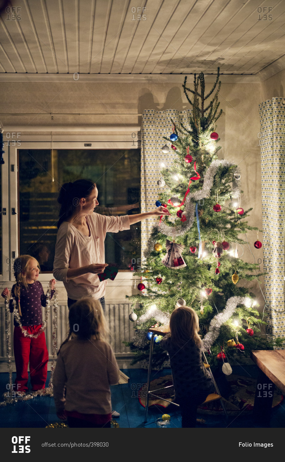 Finland, Mother with daughters (12-17 months, 2-3, 4-5) decorating christmas tree